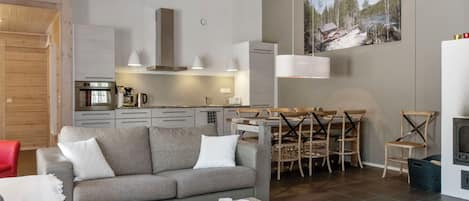 A modern living room with a grey sofa, a wooden coffee table, and a dining area with a wooden table and chairs.