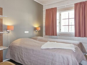 A room with two beds, a window with curtains, and wall-mounted lamps. - Hampus holiday home by Interhome (Salla)