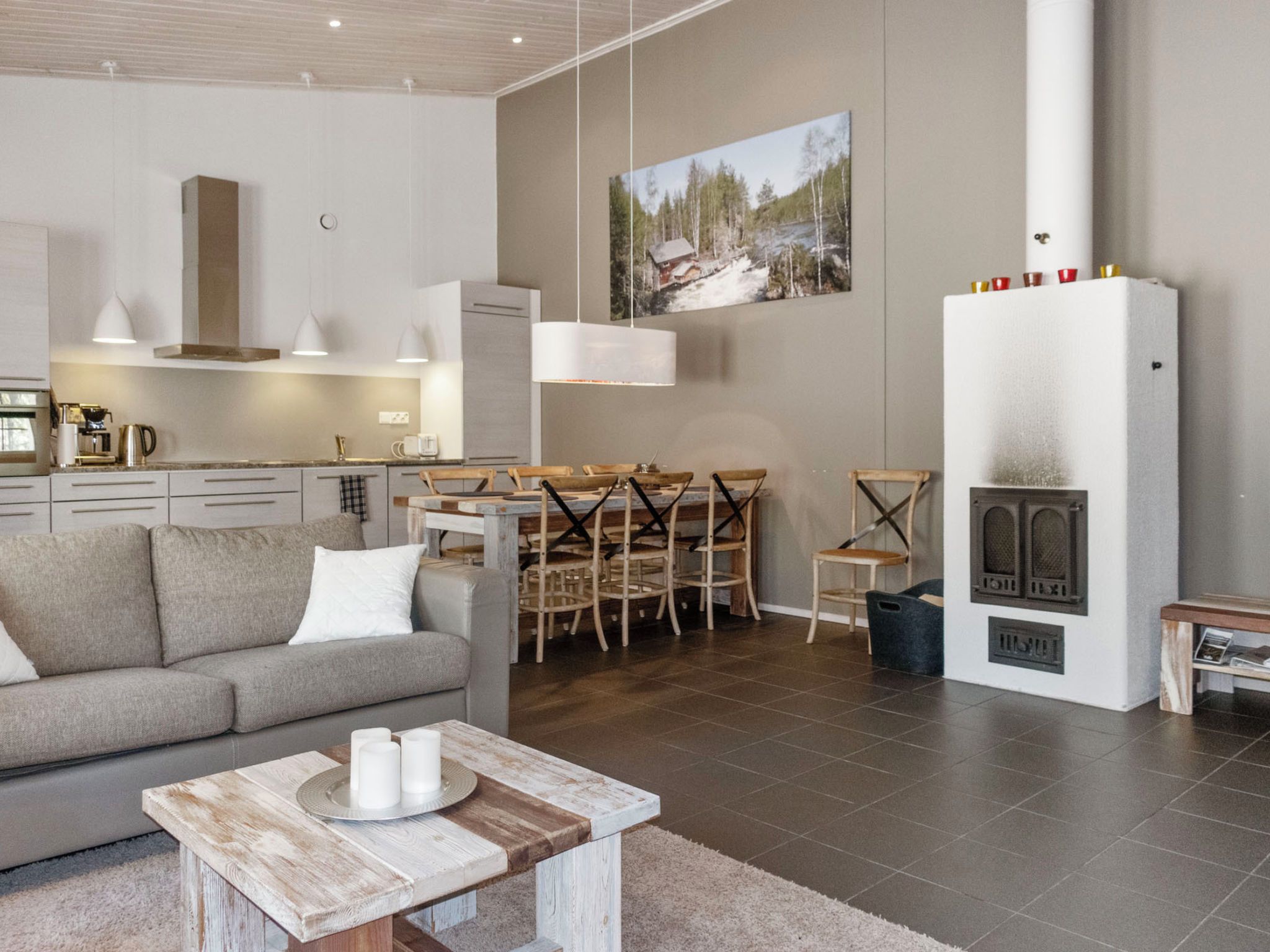 Uma sala de estar moderna com sofá, mesa de jantar com cadeiras, lareira e cozinha ao fundo.