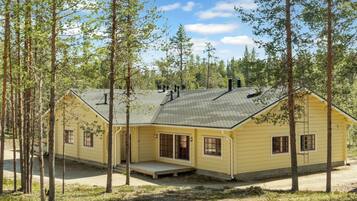 A single-story yellow building with a flat roof, surrounded by tall trees.