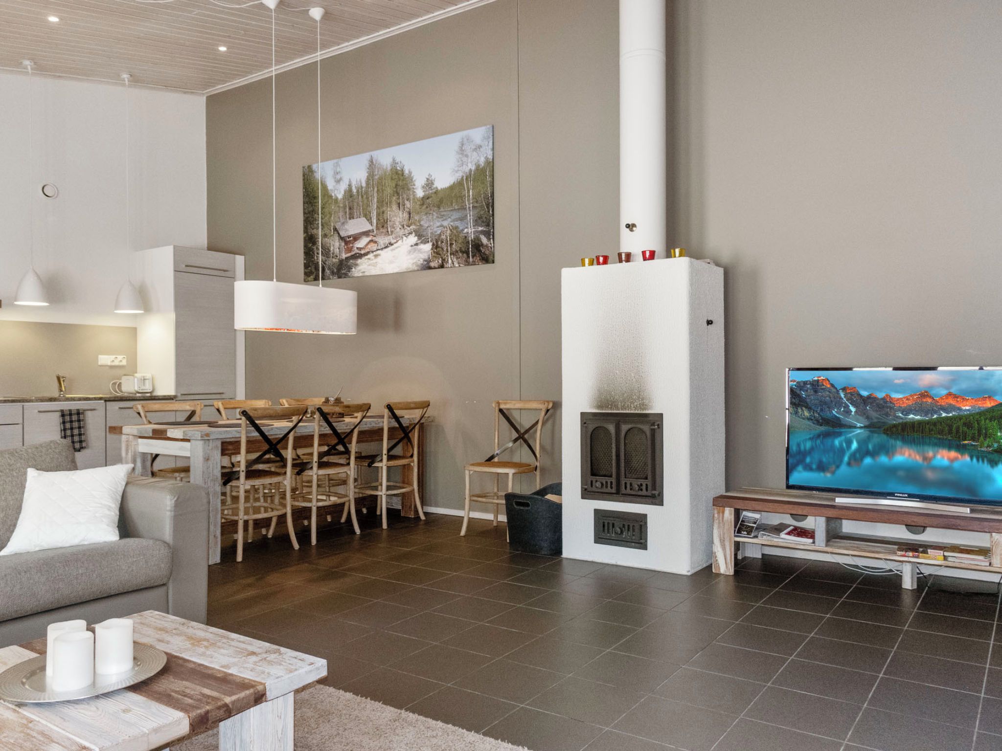 A modern living room with a fireplace, dining area, and a large flat-screen TV.