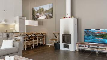 A modern living room with a fireplace, dining area, and a large flat-screen TV.