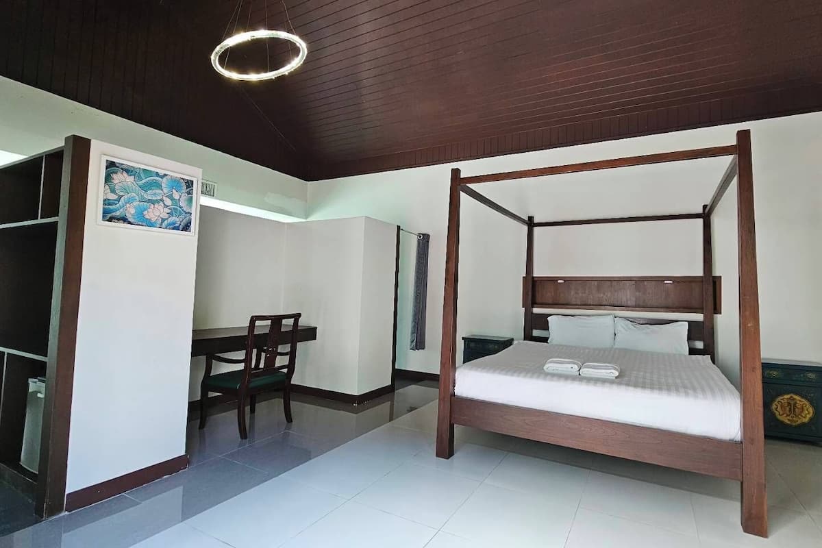A room with a four-poster bed, a desk, and a chair.