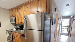 Una cocina con armarios de madera, electrodomésticos de acero inoxidable y un suelo con patrón de espiga.