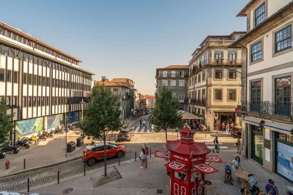 A street view with a red kiosk, a crosswalk, and buildings with balconies.
