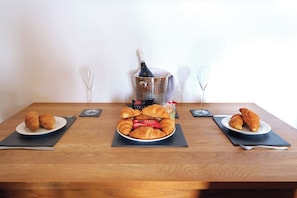 Ein Holztisch mit Croissants, einer Champagnerflasche und zwei Gläsern.