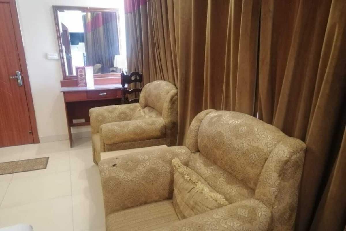 A room with two patterned sofas, a wooden desk with a mirror, and a brown curtain.