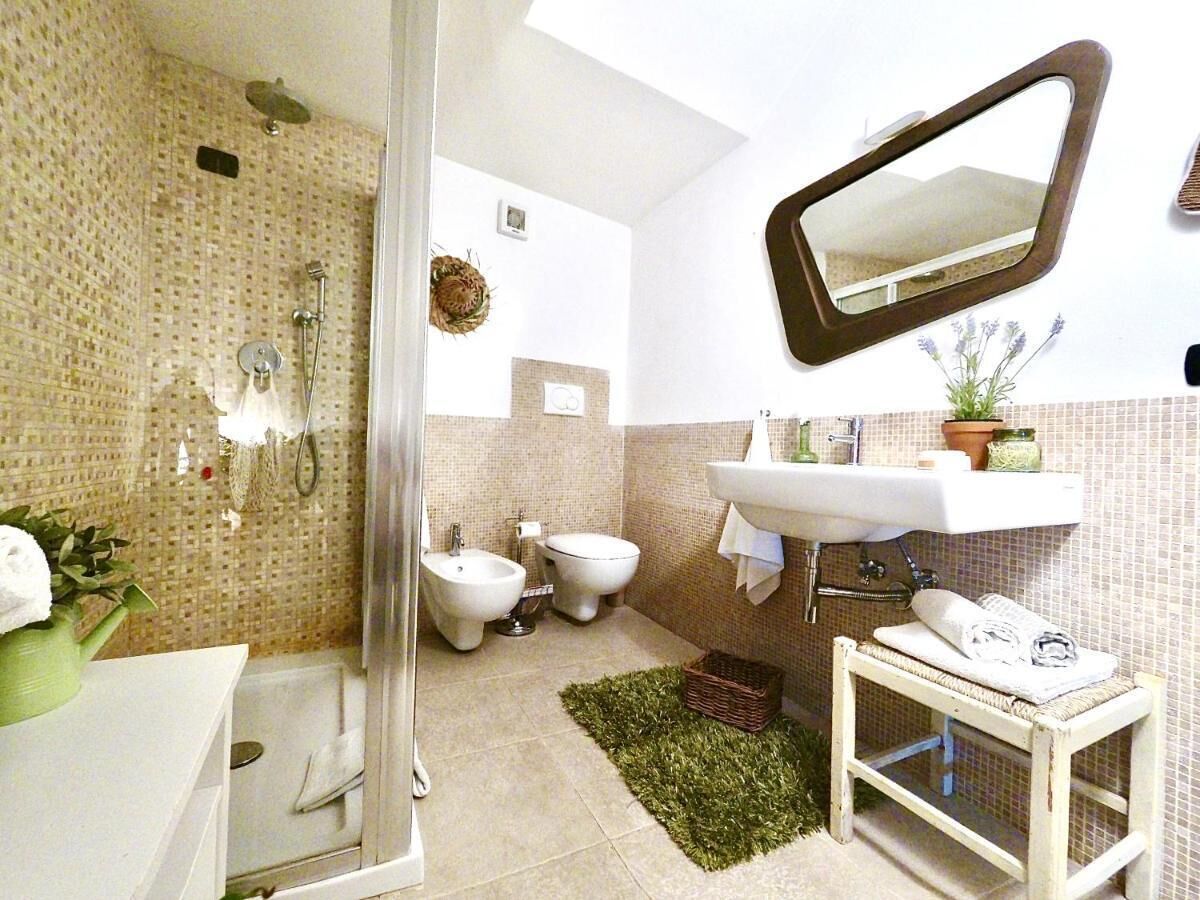 A bathroom with a shower, bidet, sink, and a mirror.