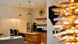 A modern kitchen with pendant lighting, a dining area with a sofa, and a decorative wall piece. - Studio Private Pool Natural Lighted Boho Chic (Tulum)