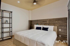 A modern bedroom with a large bed, a wooden headboard, and a black metal shelving unit.