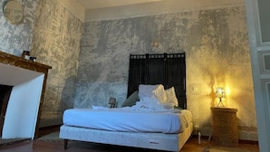 A bedroom with a bed, a bedside table, a lamp, and a wall with a textured pattern. - Roquefort des Corbières house (Roquefort-des-Corbières)