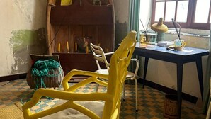A room with a checkered floor, a yellow chair, a table with a lamp, and a window with blinds. - Roquefort des Corbières house (Roquefort-des-Corbières)
