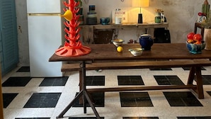 A kitchen with a wooden table, a refrigerator, and a tiled floor. - Roquefort des Corbières house (Roquefort-des-Corbières)