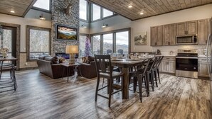 A spacious kitchen with a stone accent wall, large windows, and a high ceiling. - Topside Splash | Pool, Hot Tub & Mountain Views (Gatlinburg)