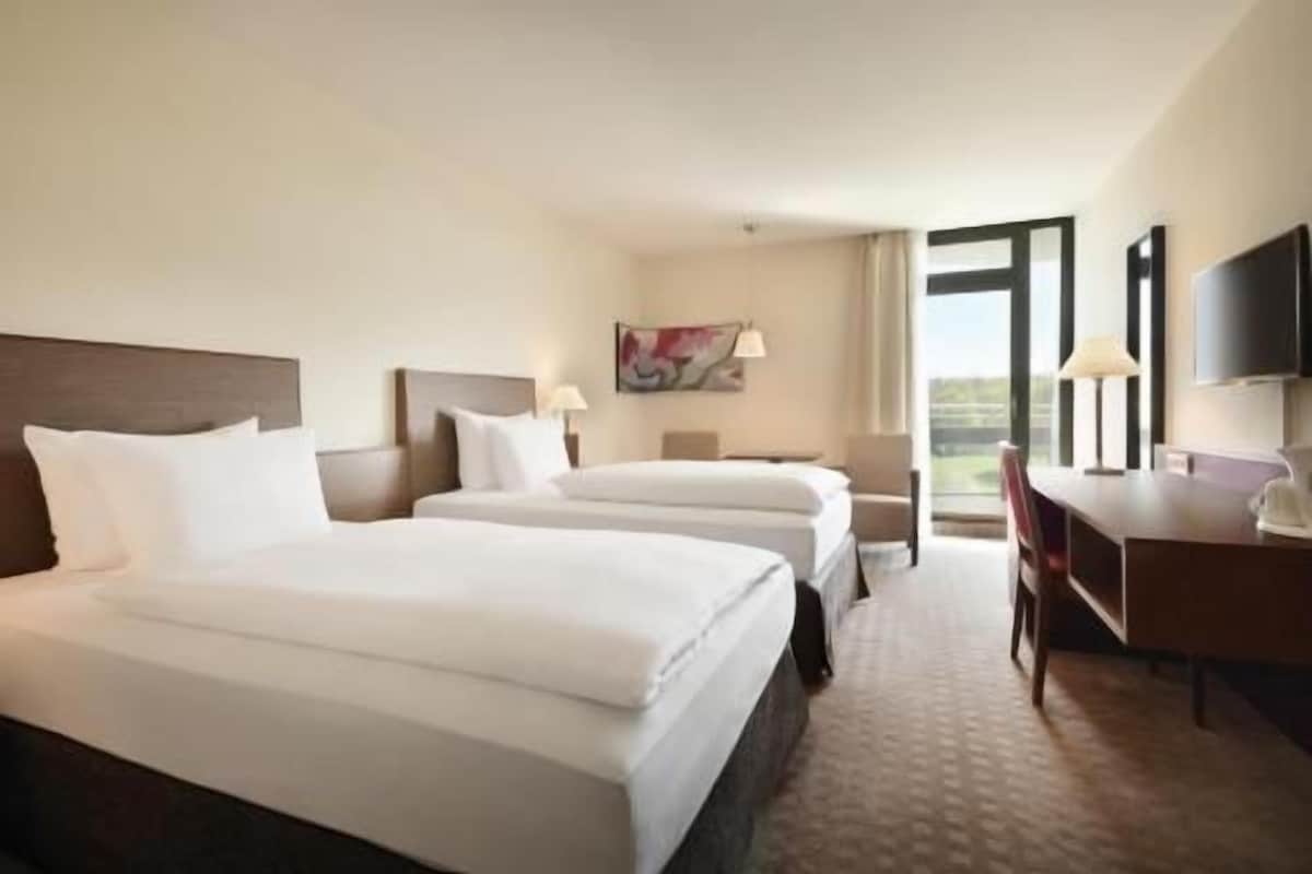 Une chambre d’hôtel avec deux lits, un bureau et une chaise.