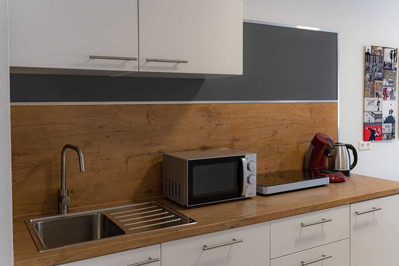 A modern kitchen with a stainless steel sink, a microwave, and a kettle on the counter.