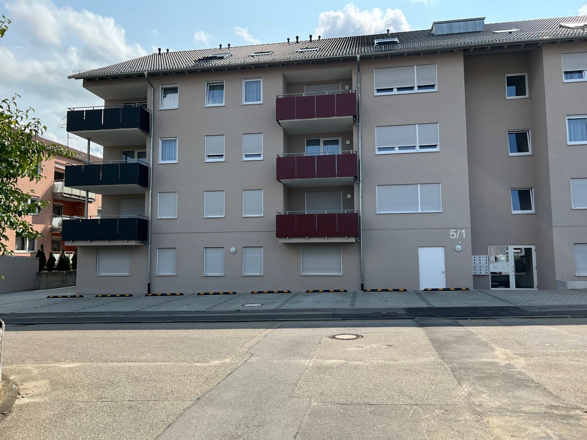 Un edificio residencial de varios pisos con balcones, una entrada a nivel de calle y un número de puerta visible.