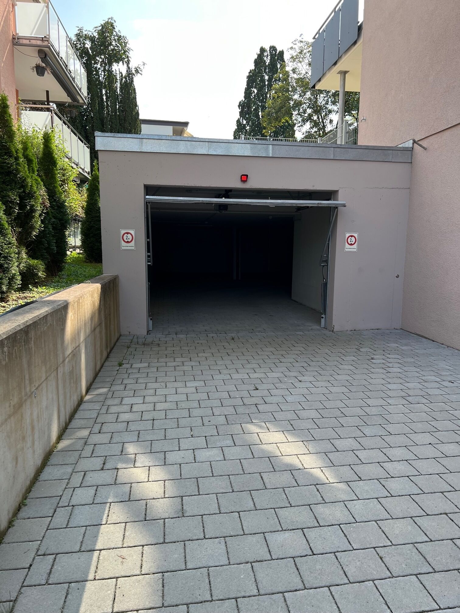 A covered parking garage entrance with a brick pathway leading to it.