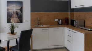 A modern kitchen with white cabinets, a wooden countertop, a sink, a coffee maker, and a microwave. - New Age Boardinghaus Bad Wimpfen (Bad Wimpfen)
