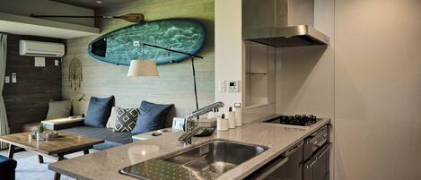 A modern kitchen with a large island, stainless steel appliances, and a unique wall-mounted surfboard decoration.