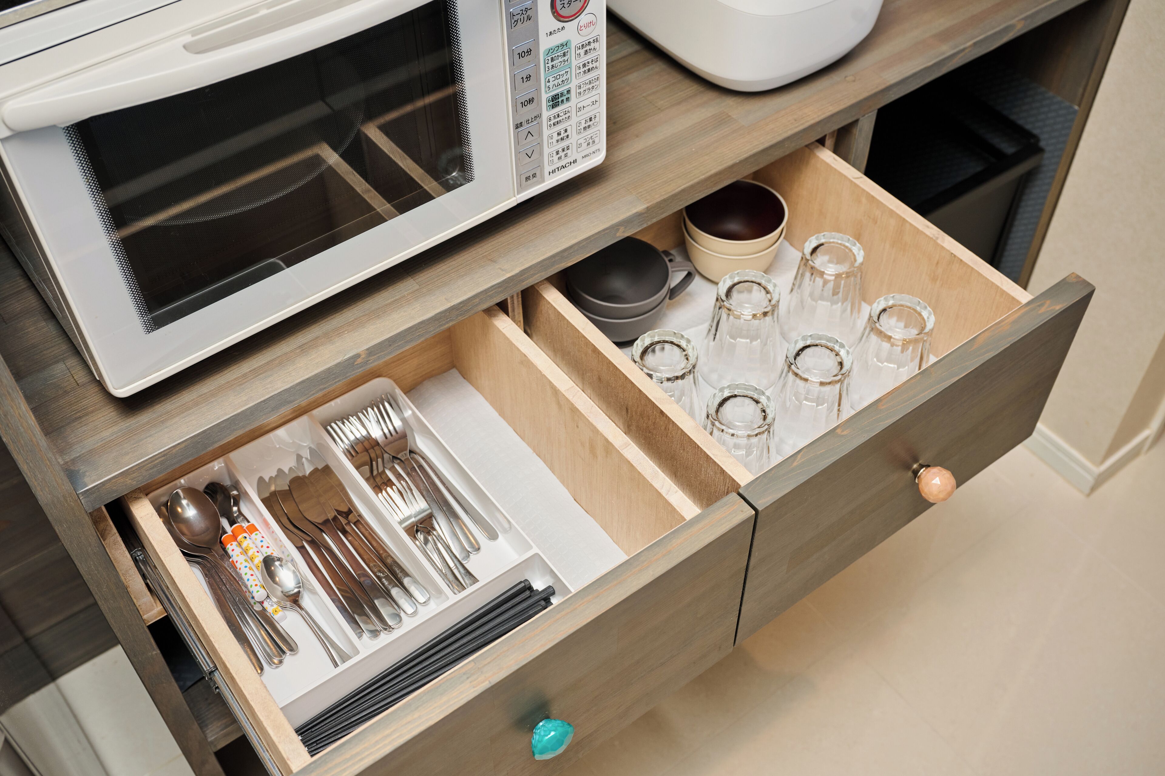 A kitchen drawer with utensils and glasses.