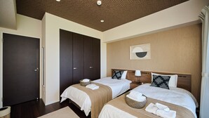 Habitación de hotel con dos camas, cabecero de madera, una obra de arte en la pared y una puerta oscura.