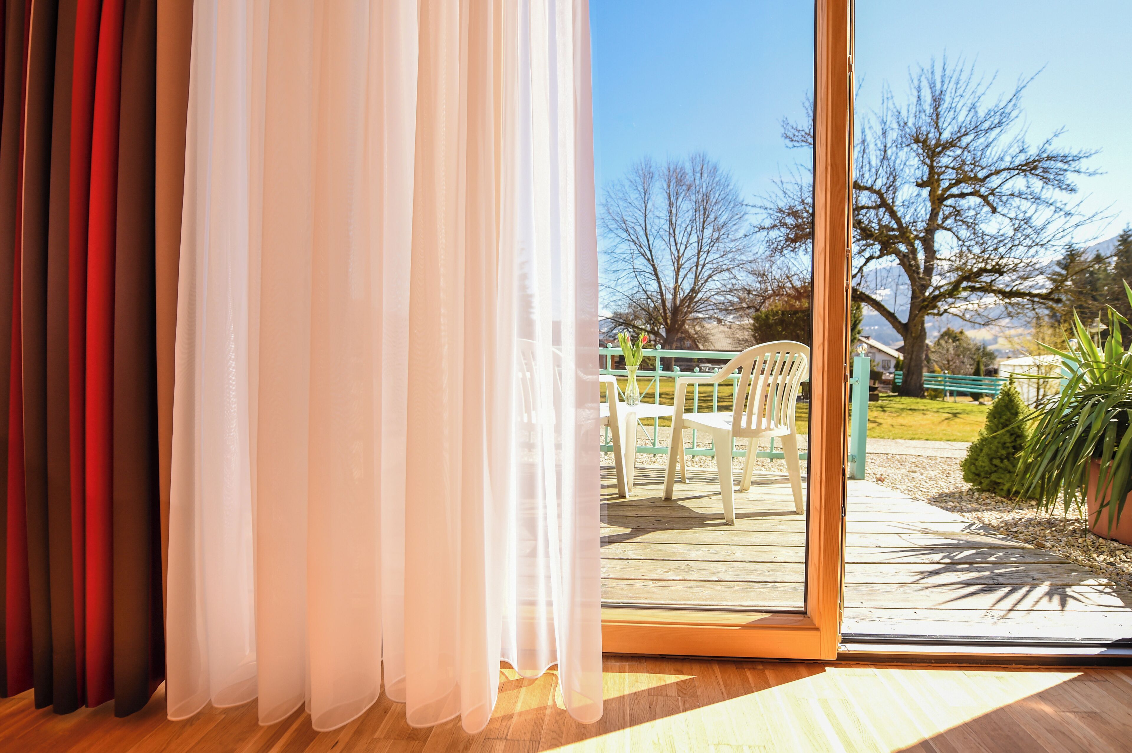 Una habitación con puerta corrediza de vidrio que da a una terraza exterior con mesa y sillas.