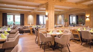 A restaurant with wooden beams, multiple dining tables, and chairs.