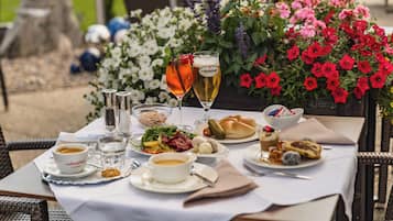 A table set with various dishes, drinks, and a floral backdrop.