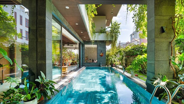 Una piscina interior con agua cristalina, rodeada de plantas en macetas y arquitectura moderna.