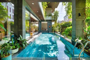 An indoor swimming pool with clear water, surrounded by potted plants and modern architecture. - Luxury Duplex Penthouse With Pool Foosball (Da Nang)