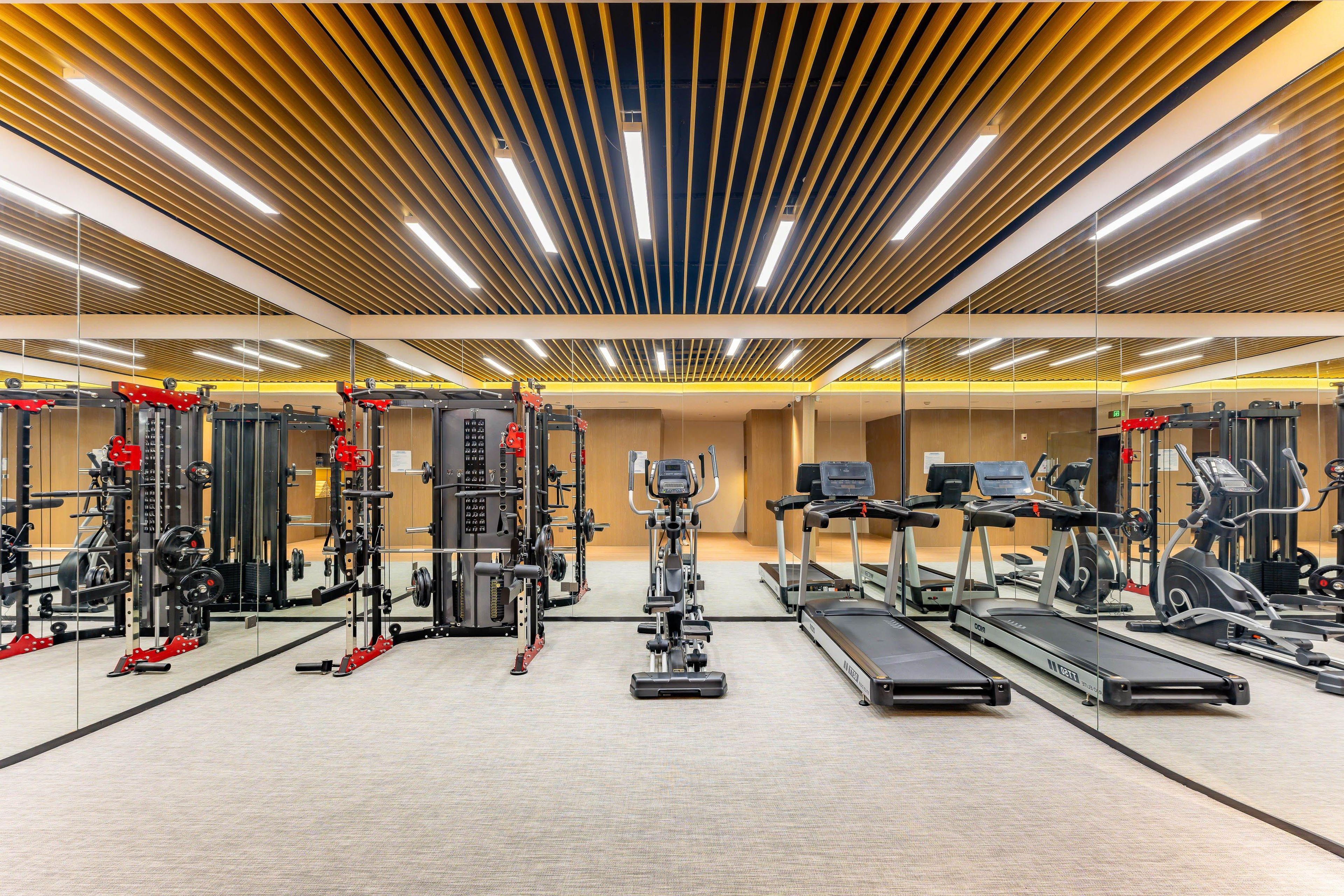 A modern gym with various exercise equipment, including treadmills, weight machines, and free weights.