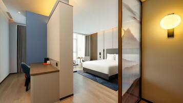 Una habitación de hotel moderna con escritorio, cama y un gran ventanal.