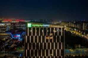 Ein Holiday Inn Express Gebäude mit modernem Design, gekennzeichnet durch beleuchtete vertikale Linien und eine auffällige Beschilderung.