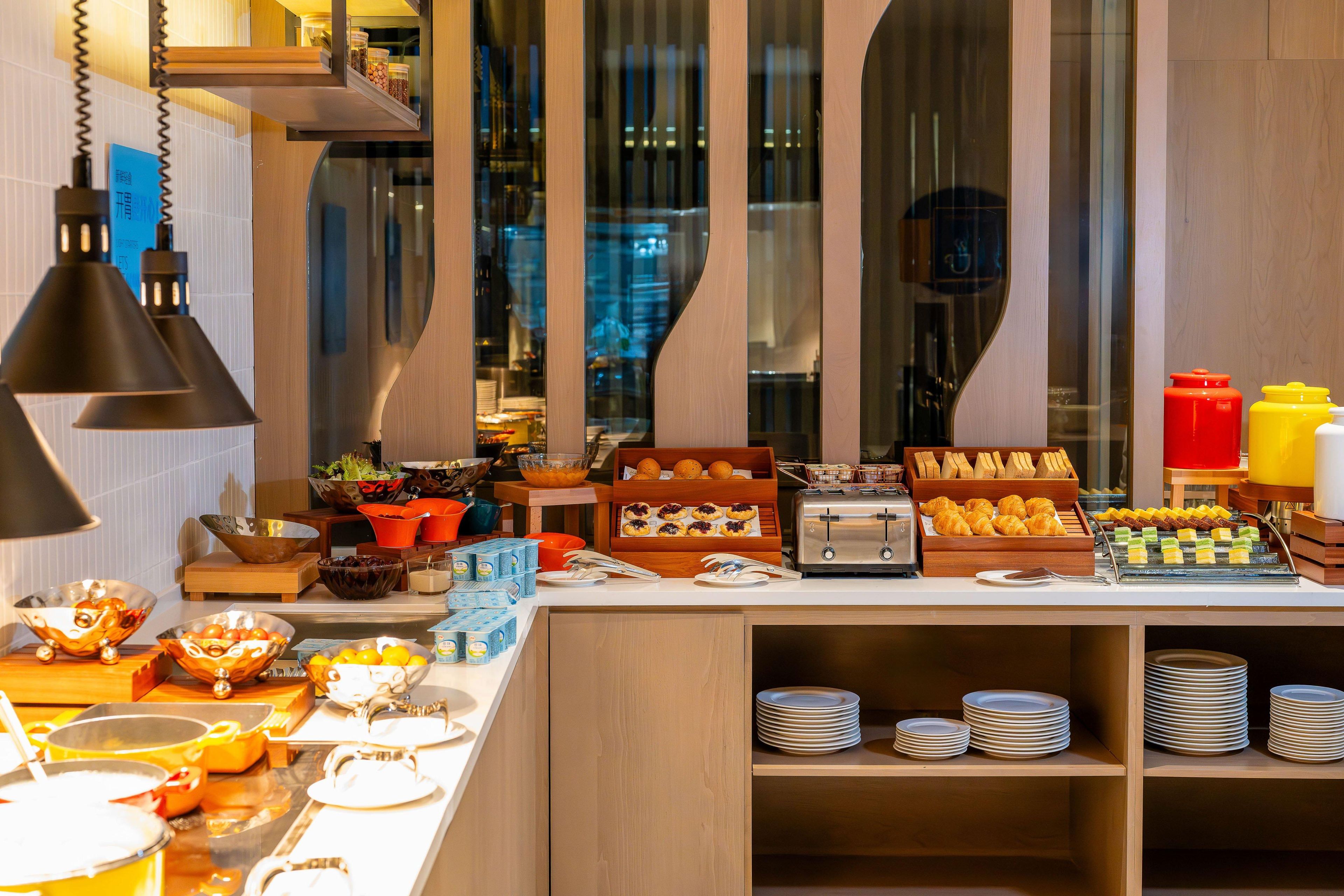 Um buffet de café da manhã com diversos alimentos e utensílios.