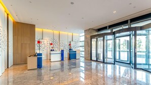 A modern lobby with a marble floor, glass doors, and two reception desks. - Holiday Inn Express Suzhou Bay (Suzhou)