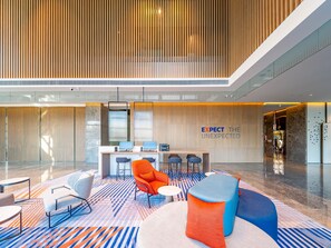 Eine moderne Lobby mit einer Rezeption, einer Sitzgelegenheit und einem großen Fenster.