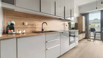 A modern kitchen with a wooden countertop, stainless steel appliances, and a large window offering a view of the city.