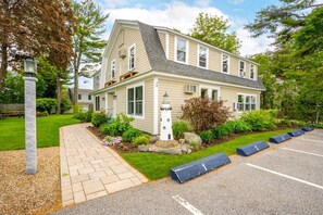 A two-story house with a sloped roof, a front porch, and a small garden area with a stone lantern. - Beautiful inn, Lighthouse Landing. #3 Sea Glass (Ogunquit)