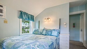 A bedroom with a bed, a dresser, a window with curtains, wall-mounted lights, and a door. - Beautiful inn, Lighthouse Landing. #3 Sea Glass (Ogunquit)