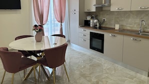 A modern kitchen with a marble countertop, stainless steel appliances, and a dining area with a round table and chairs. - Apartment bari center (Bari)