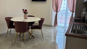 A modern kitchen with a stainless steel sink, a dining area with a marble table, and a flat-screen TV mounted on the wall. - Apartment bari center (Bari)