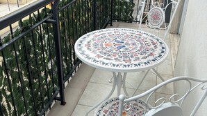 A balcony with a round table and two chairs, a metal railing, and a view of buildings. - Apartment bari center (Bari)