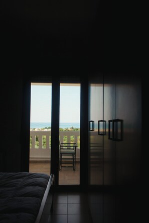 A bedroom with a bed, a balcony, and a view of the sea. - Villa Cook with pool and sea views (Platanias)