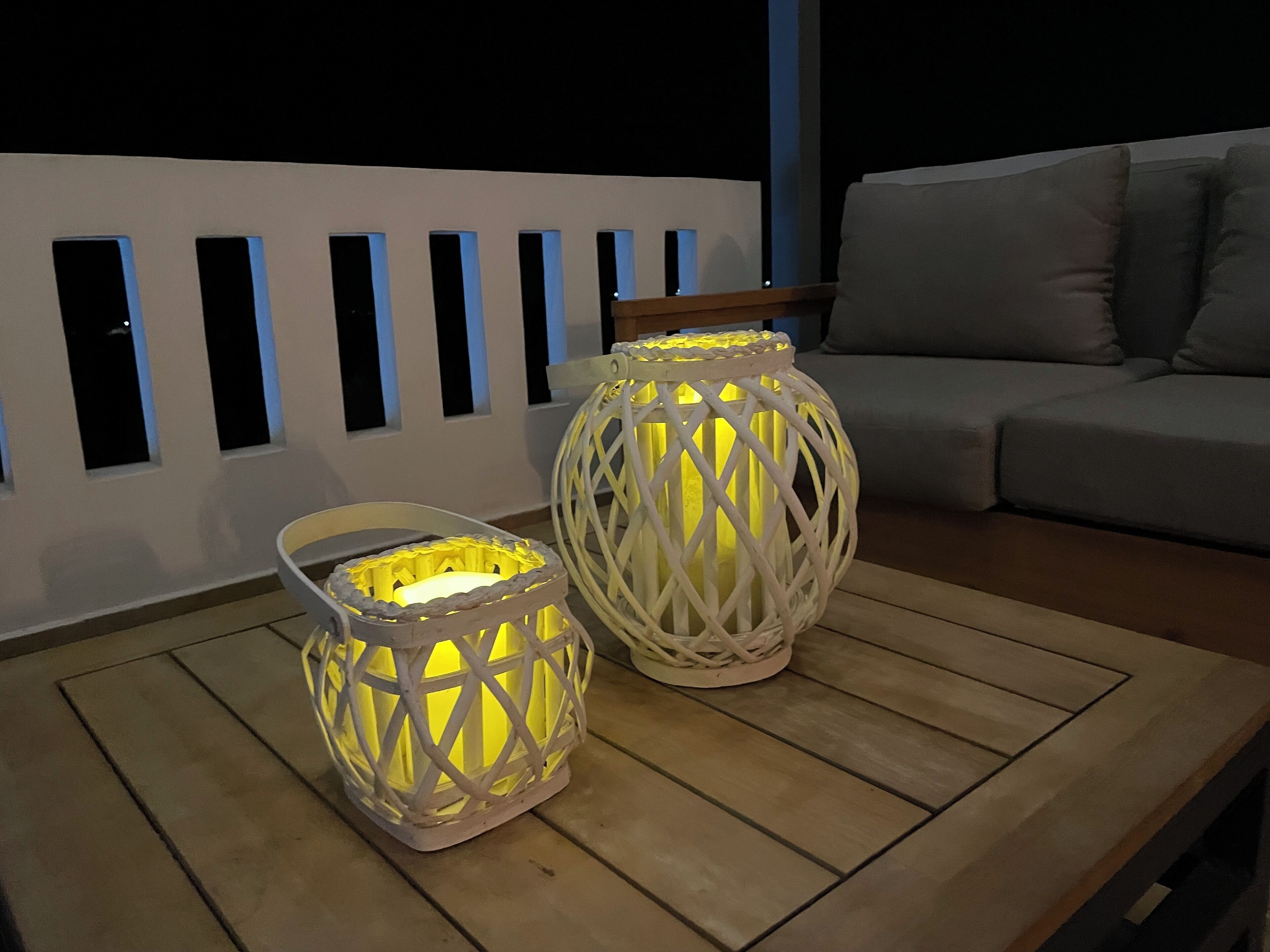 Two white lanterns with yellow lights on a wooden table.