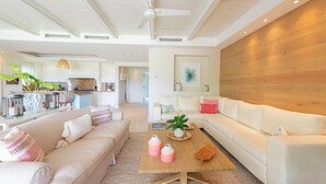 A spacious living area with a large white sofa, a wooden coffee table, and a kitchen in the background. - Luxurious 4 Bedroom Condo (Punta de Mita)