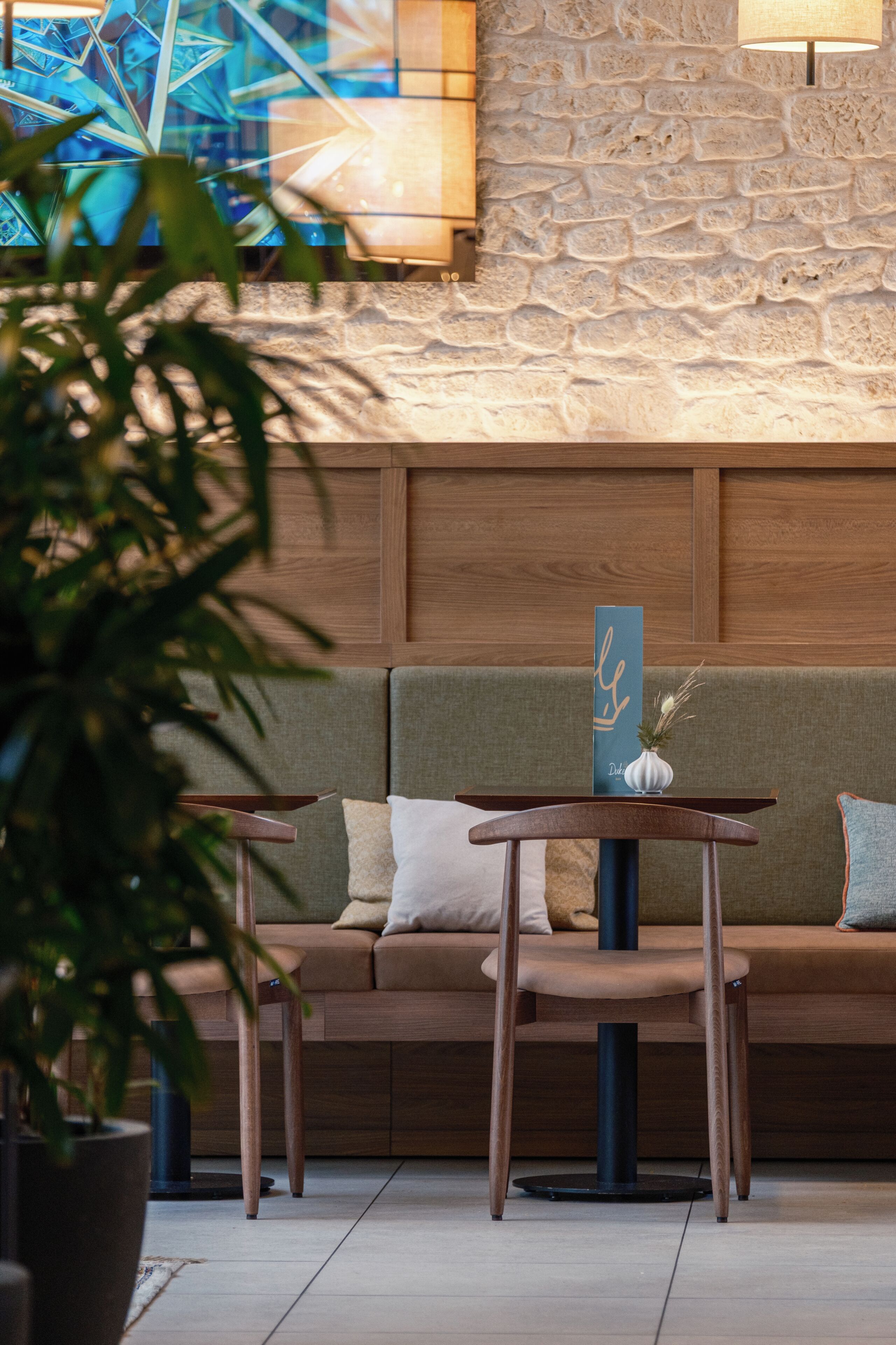 A modern interior with a wooden bench, a cushioned seating area, and a stone wall.