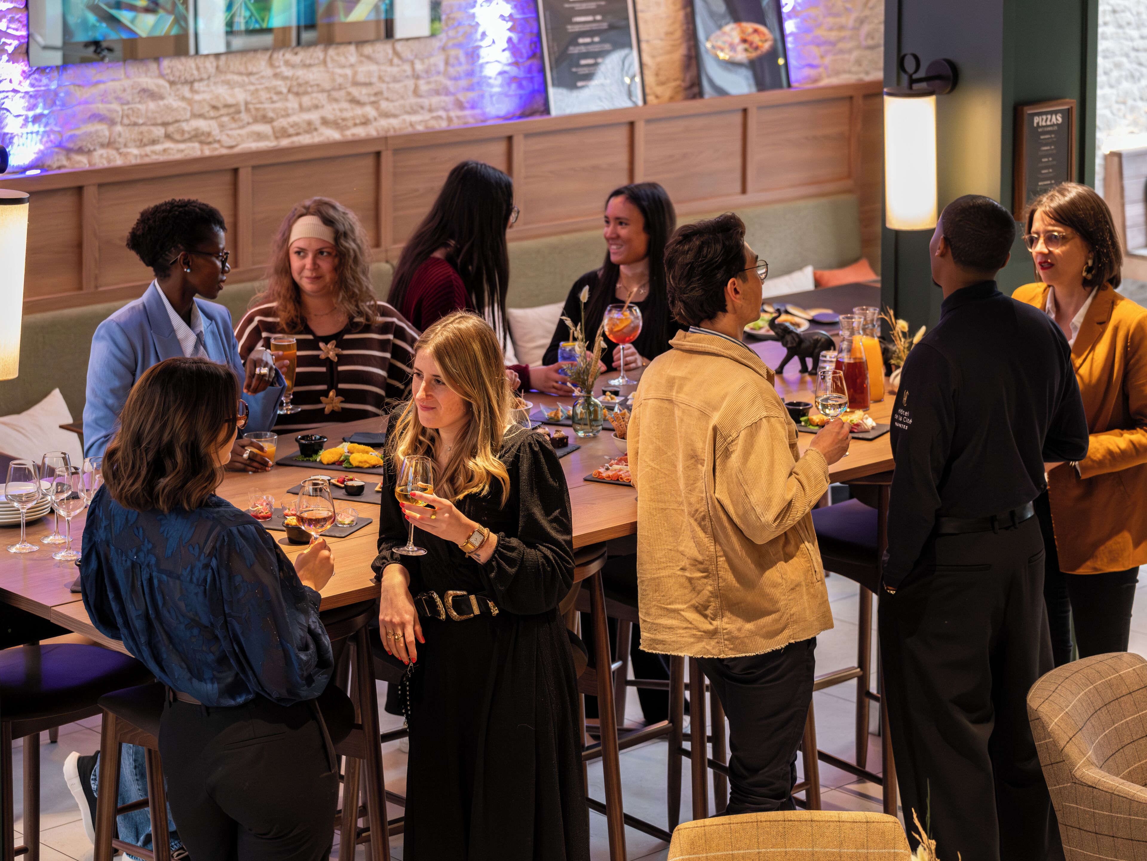 A group of people seated at a bar with a menu board in the background.