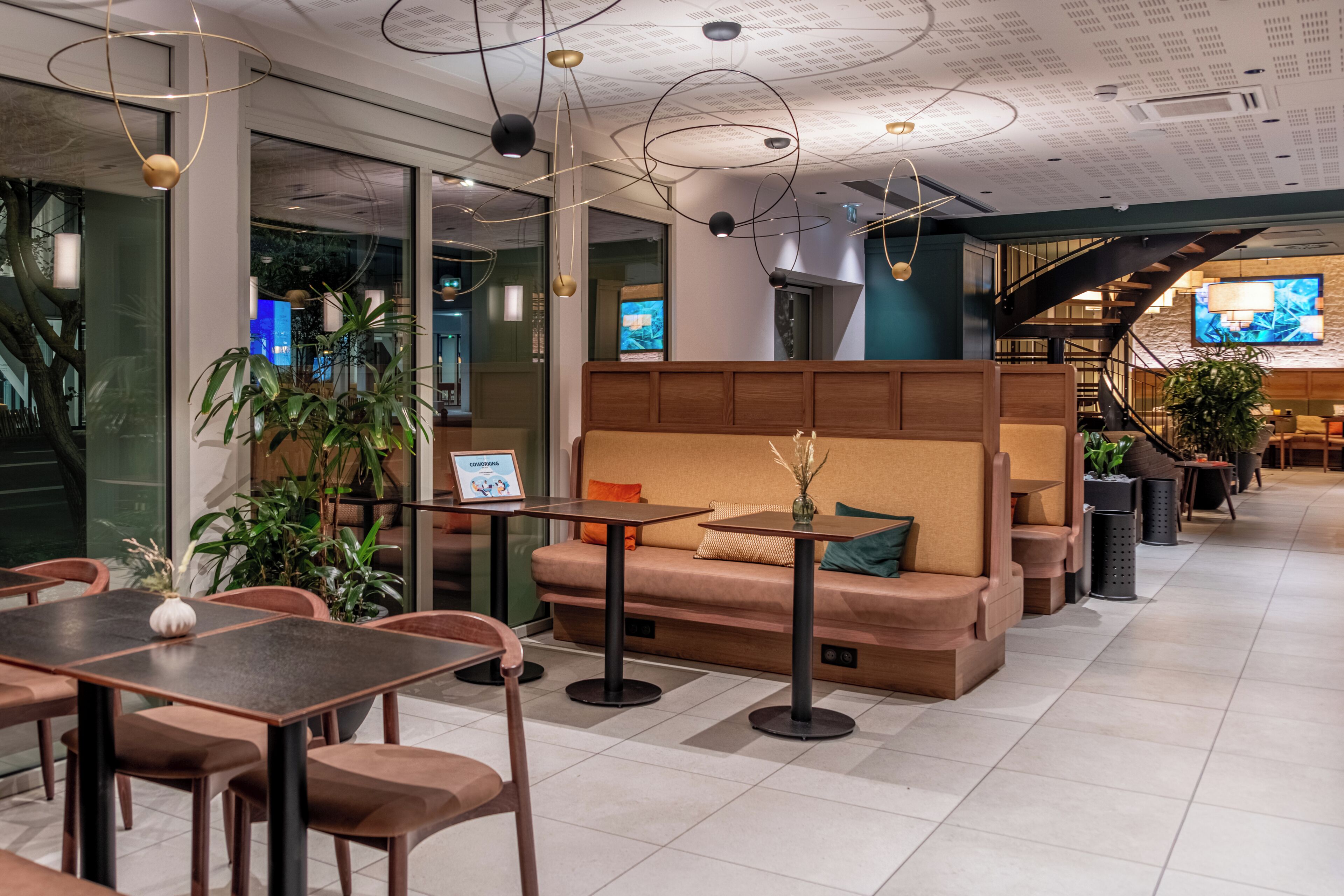 A modern interior with a seating area, tables, and a staircase.