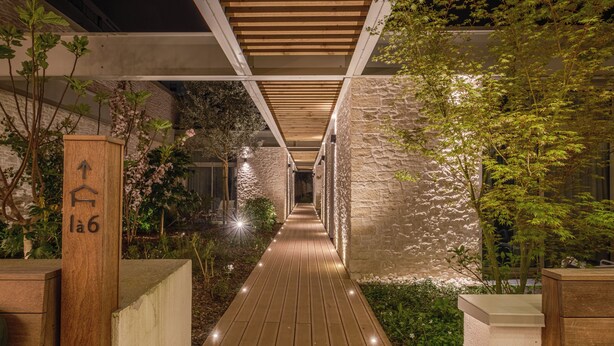 Un sendero de madera que conduce a un edificio de paredes de piedra y follaje.